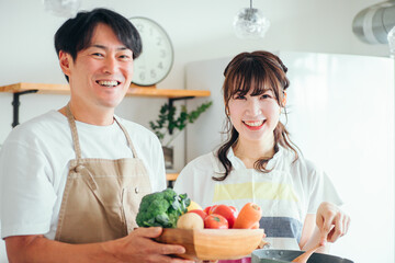 一緒に料理を作る男女（夫婦・フライパンと野菜）
