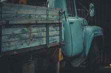 Blurred Abandoned Truck In A Village. An Old, Failed Blue Truck. Wooden Sides Of The Body. Selective Focus, Grain