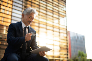 Senior businessman with digital tablet. Man holding credit card