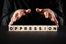 Male Hands Over The Wooden Blocks With The Word Oppression. Domination, Harassments, Abuse Or Discrimination