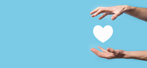 Wall Mural - Male hand holding heart , like icon on blue background. Kindness, charity, pure love and compassion concept.Banner with copy space