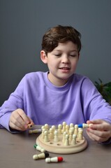 A cute boy in purple sweatshirt is playing memory chess.