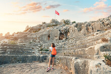Elegant Tourist Girl Explores Ancient Landmark And Ruins Of Greek Or Roman Amphitheater In Simena Castle, Turkey