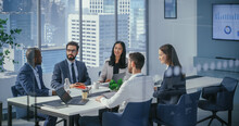 Modern Multi-Ethnic Office Conference Room Meeting: Diverse Team Of Managers, Executives Talk, Brainstorm, Use Computers. Businesspeople Discuss Investment Strategy In E-Commerce Startup.
