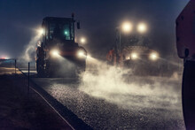 Rolling Asphalt At Night With Headlights. Road Construction.