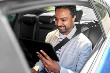 Wall Mural - transportation, vehicle and people concept - smiling indian male passenger with tablet pc computer in taxi car