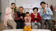 © PRPicturesProduction - family looking at camera, filming happy chinese new year wish video with congratulation gesture at home. cheerful asian woman making come here hand sign as the man running over