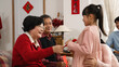 © PRPicturesProduction - smiling asian grandfather and grandmother gesturing at granddaughter to come and giving lucky money to her in the living room on chinese new year. text translation: spring and congratulations