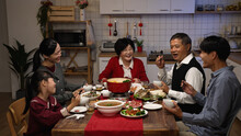Cheerful Asian Family Members Having Fun Chatting And Laughing At Dining Table While Enjoying Big Meal On Chinese New Year's Eve Dinner Party At Home