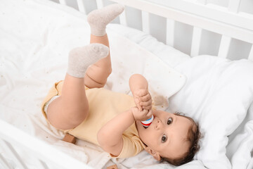 Sticker - Cute little baby with toy lying in comfy crib