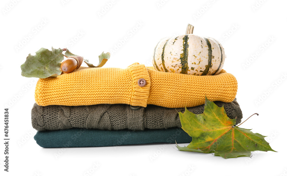 Stack of baby clothes, pumpkin and leaves on white background