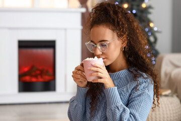 Sticker - Pretty young woman with cup of tasty hot chocolate at home on Christmas eve