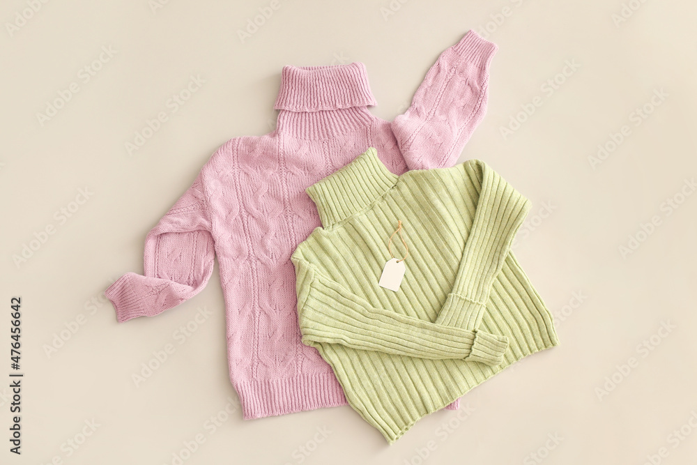 Stylish roll-neck sweaters and blank price tag on light background