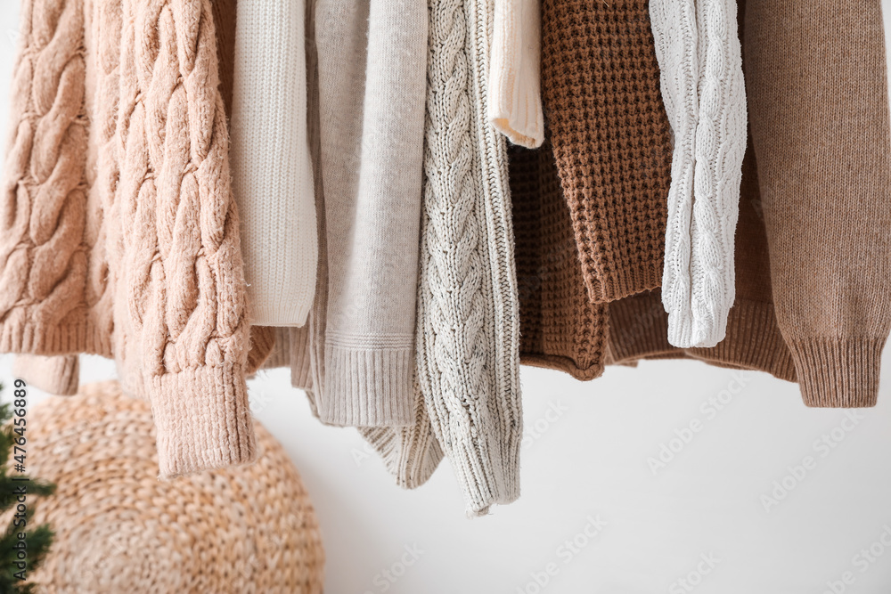 Stylish sweaters hanging in dressing room