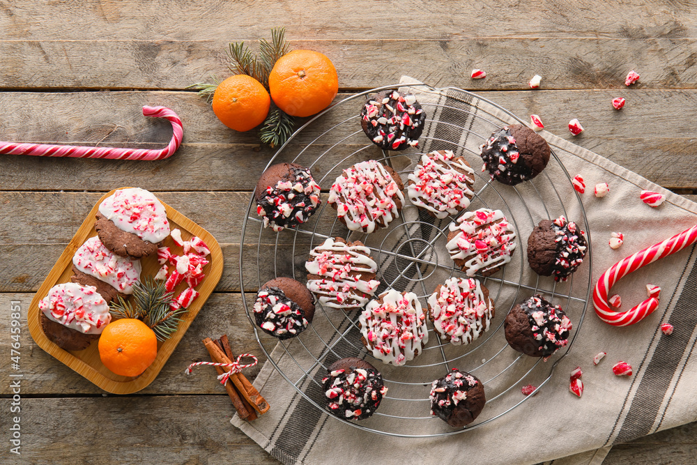Board and grid with tasty candy cane cookies on wooden background