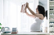 © Diego - young pregnant woman ironing, folding and preparing clothes for her future baby. preparation of the room and arrival of the newborn