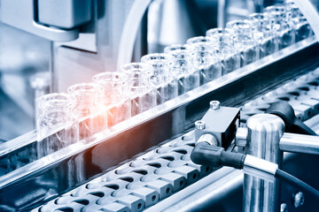 Glass bottles in production in the tray of an automatic liquid dispenser; a line for filling medicines against bacteria and viruses; antibiotics and vaccines.