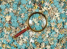 Puzzle Mess And Chaos Through Magnifying Lens. Missing Jigsaw Piece Among Scattered Parts. Overflow Of Information Concept.
