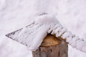 An ax and a log covered with snow. Chopping (preparation) of firewood.