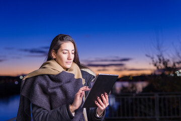 Spanish young woman use digital tablet technology internet during sunset near Tajo river Toledo