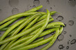 Green beans sit on a slate cutting board after being trimmed and washed