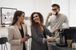 © New Africa - African American woman talking with colleagues while using modern coffee machine in office