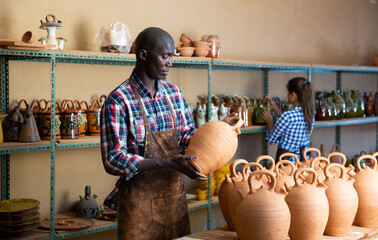 Two positive smiling potters in the process of work at the workshop. High quality photo