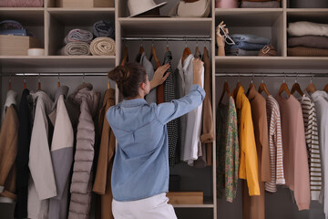 Canvas Print - Young woman choosing clothes in wardrobe closet, back view