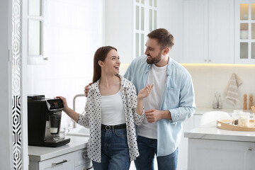 Canvas Print - Happy couple preparing fresh aromatic coffee with modern machine in kitchen