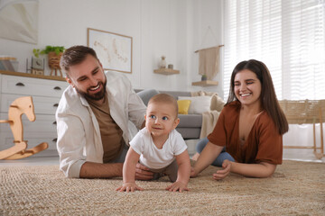 Wall Mural - Happy parents watching their baby crawl on floor at home