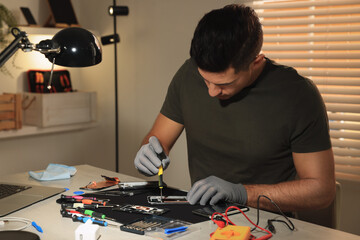 Wall Mural - Technician repairing broken smartphone at table indoors