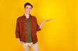 © Tetiana - Photo of young man hold hand promotion advertise select recommend present isolated over yellow color background