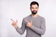 © Tetiana - Photo of young guy good mood indicate fingers empty space promoter advise ads isolated over grey color background