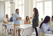 © Studio Romantic - Course trainer, psychologist or business coach training group of people. Adult Caucasian students sitting at tables in classroom, answering teacher's questions, learning new things. Education concept