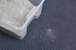 A litter box with clumping litter sits on a honeycomb EVA mat. Small filler particles from the feet remain in the cells. Order and cleanliness in the house.