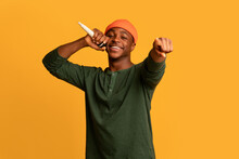 Joyful Young Black Man Singing With Microphone And Pointing At Camera