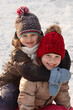 © Maryana - Winter children in snow backcground. Two winter girls hugging smiling. Winter girls portrait.