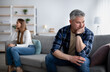 © Prostock-studio - Offended mature man and woman sitting on different sides of sofa after after quarrel indoors, empty space