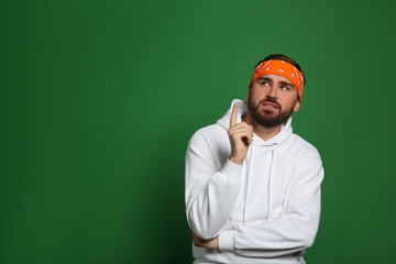 Wall Mural - Fashionable young man in stylish outfit with bandana on green background, space for text