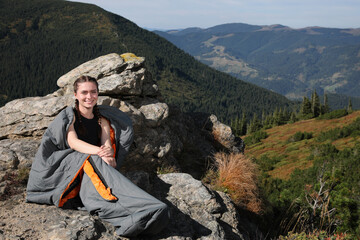 Wall Mural - Happy tourist in sleeping bag on mountain peak