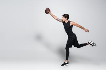 Wall Mural - Side view of player with rugby ball running on grey background