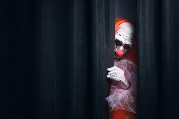 Wall Mural - Terrifying clown hiding behind black curtains, space for text. Halloween party costume
