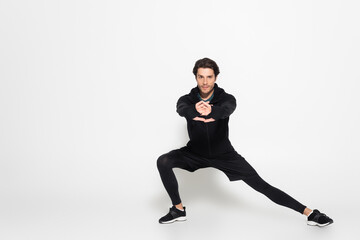 Wall Mural - Brunette sportsman looking at camera while training on grey background