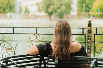 girl with her back in the park on a summer day sitting on a bench