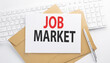 © Iryna - Text JOB MARKET on the envelope on the keyboard