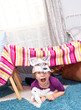 A child in a wolf mask, plays in the children's room. The child built a tent with chairs and bedspreads.