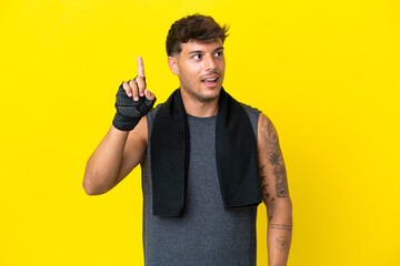 Wall Mural - Young sport caucasian man with towel isolated on yellow background intending to realizes the solution while lifting a finger up