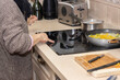 © mialcas - A woman turning on the ceramic hob in the kitchen. Housework concept.