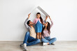 © Prostock-studio - Housing for young family concept. Young eastern father, mother and daughter under symbolic roof over light wall