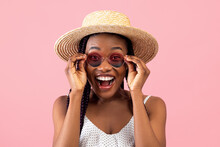 Excited Millennial African American Woman In Summer Wear Touching Her Sunglasses, Shouting WOW Over Pink Background